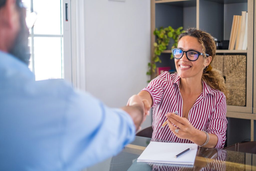 Smiling caucasian female hr manager handshake hire male candidate at job interview make good first impression, happy mixed race client shake hand of bank broker, respect, business agreement concept